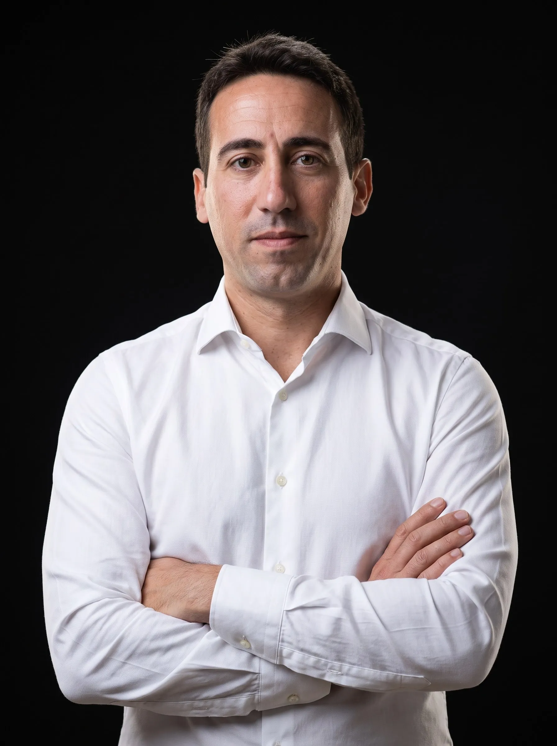 Manuel Liria, con camisa blanca y los brazos cruzados, sobre fondo negro de estudio